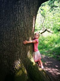 Full length of woman standing by tree trunk