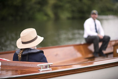 Rear view of man sitting on boat in lake