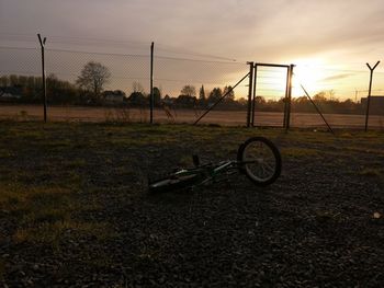 Bicycle on field against sky during sunset