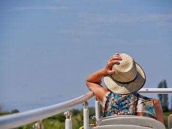 Man wearing hat against railing against clear sky