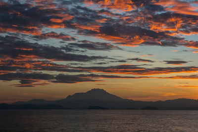 Scenic view of dramatic sky over silhouette mountains during sunset