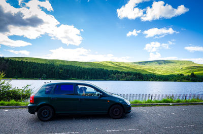 Car on road by trees against sky