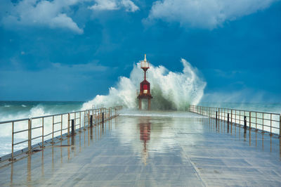 Rear view of man on lighthouse by sea against sky