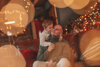 Candid authentic happy dad playing with little son fooling around at wooden lodge xmas decorated