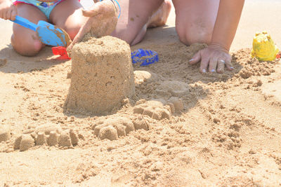 Low section of boy playing with toy on sand