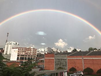 Rainbow over city against sky