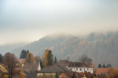 Houses and trees against sky during winter