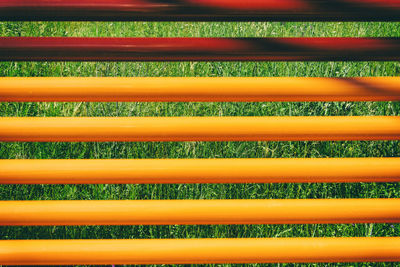 Full frame shot of orange metallic rods over grassy field