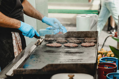 A man fries burger meatballs. man grills some kind of marinated meat on gas grill during summer time