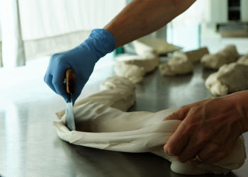 Cropped hands of person cutting bread dough