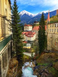 River amidst houses and trees against sky