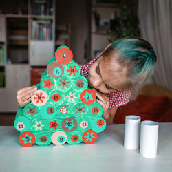 Kid making handmade advent calendar with toilet paper rolls. seasonal activity, family holidays
