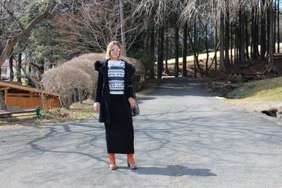 Full length of woman standing on road during sunny day