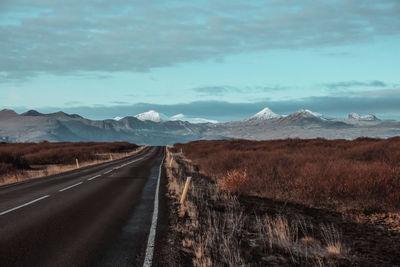 Road leading towards mountains against sky