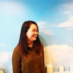 Smiling young woman standing against wall