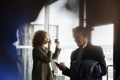 Businesswoman holding hand mirror applying lipstick before seminar at conference center