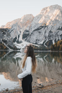 Woman standing by lake against mountains and sky