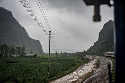 Scenic view of land against sky from train