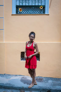 Portrait of a woman wearing red clothes on the street in bright sunny day. 