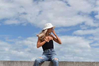 Woman wearing hat sitting against sky