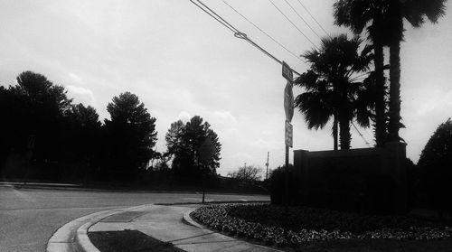 Road by trees against sky