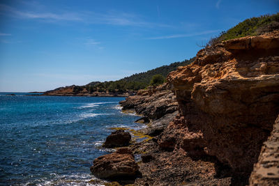 Rock formation on beach against sky