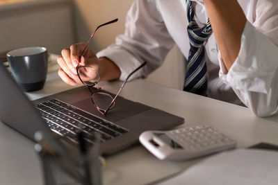 Midsection of frustrated businessman holding eyeglasses