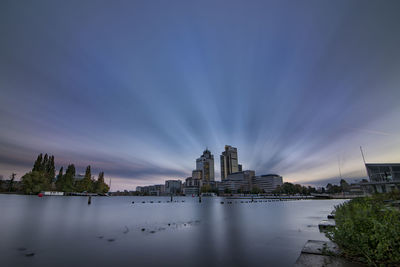 Scenic view of river by buildings against sky