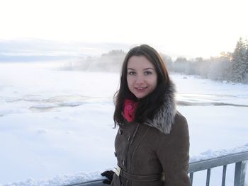 Portrait of smiling young woman standing in snow