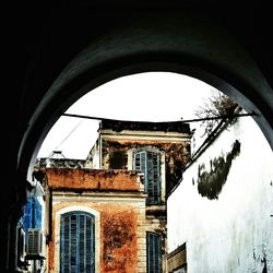 Low angle view of building against sky seen through window