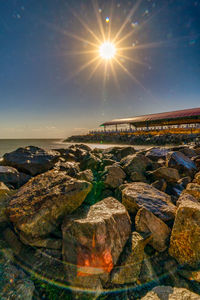 Rocks by sea against sky during sunset