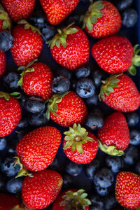 Background of assorted fresh berries of red juicy strawberries and blue blueberries close-up. 