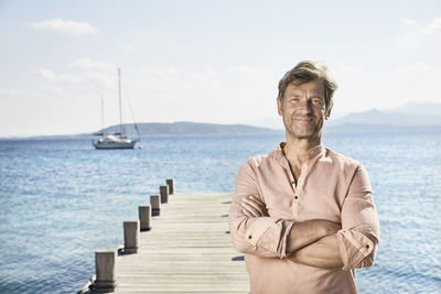 Portrait of smiling mature man standing on jetty