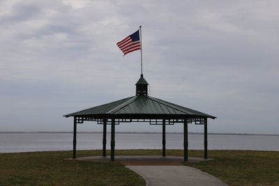 Empty shelter at lakeside park with flag flying