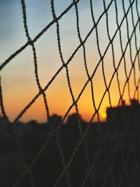 Full frame shot of chainlink fence against sky during sunset