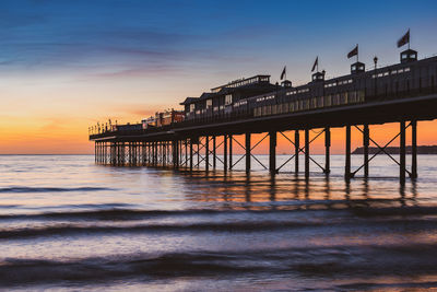 Pier over sea against sky during sunset