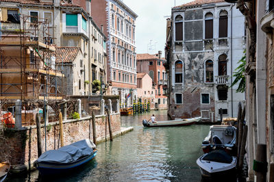 Boats moored in canal amidst buildings in city