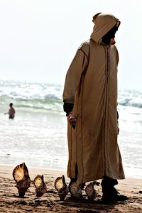 Full length of man with seashells standing at beach