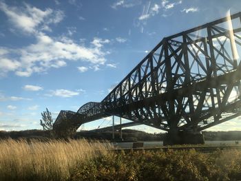 View of bridge and plants on field against sky