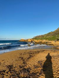 Scenic view of beach against clear blue sky