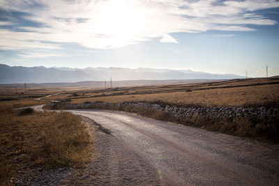 Road amidst agricultural field against sky