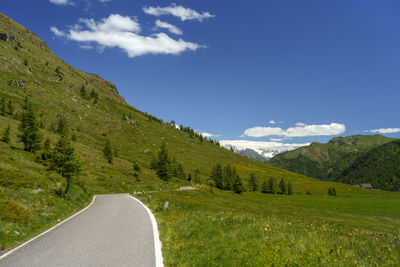 Road leading towards mountains against sky