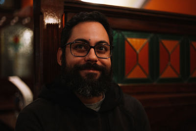 Smiling man looking away while standing against wall