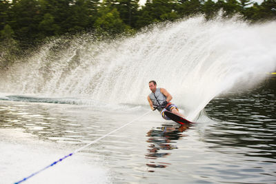 Man waterskiing in river at forest