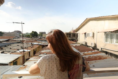 Woman standing by buildings against sky