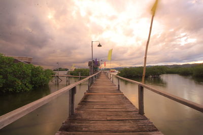 View of pier over calm sea against cloudy sky