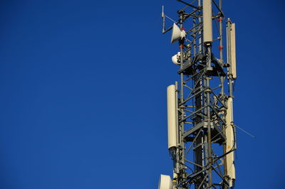 Low angle view of communications tower against blue sky