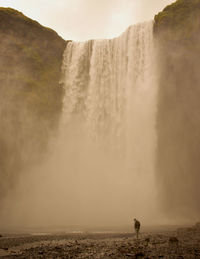 Person standing against waterfall