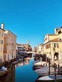 Boats in canal against clear blue sky