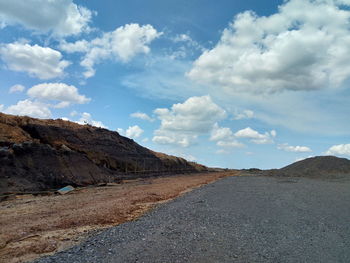 Road leading towards mountains against sky